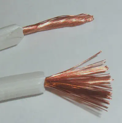 **Conductor** eléctrico de **cobre** (Cu).
https://commons.wikimedia.org/wiki/File:Stranded_lamp_wire.jpg